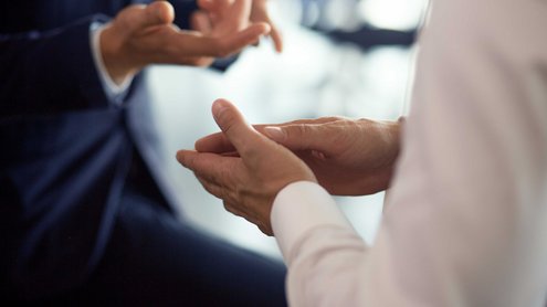 Gestikulierende Hände von zwei Personen, die im Gespräch sind.