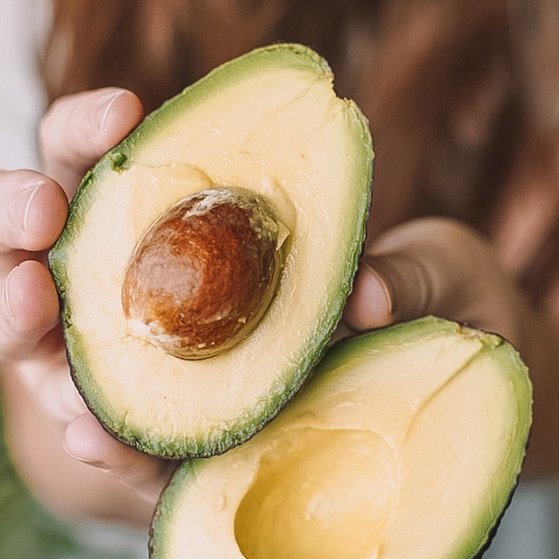 Ernährungsrisiken Woman holding sliced avocado