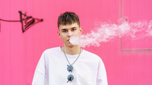 Mann dampft E-Zigarette. Frontalansicht mit Dampf 