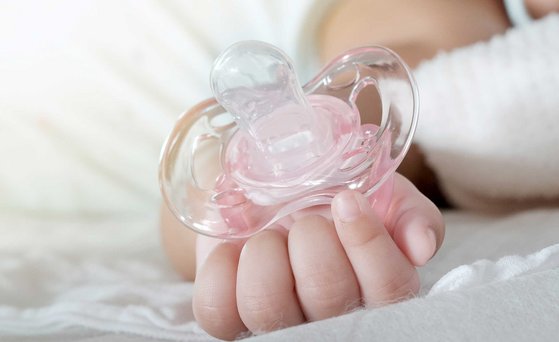 Babyhände halten rosa Schnuller.