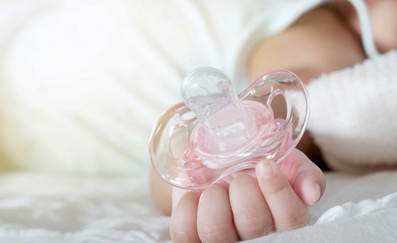 Baby hands holding pink dummy