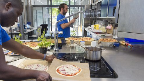 Mann packt Pizza in einer Industriek&uuml;che