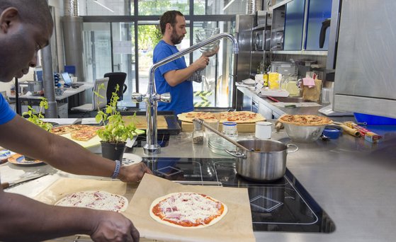 Mann packt Pizza in einer Industriek&uuml;che