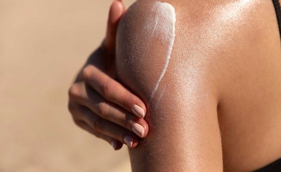 Sonnencreme wird auf Schulter aufgetragen.